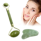 Green jade facial roller and heart-shaped gua sha stone for facial massage and skincare on a clean white background.