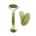 Green jade facial roller and heart-shaped gua sha stone for facial massage and skincare on a clean white background.