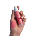 Pink liquid blush and lip tint with applicator, shown with a rosy pink swatch on the hand.