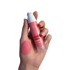 Pink liquid blush and lip tint with applicator, shown with a rosy pink swatch on the hand.